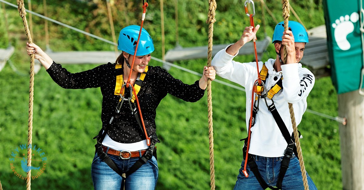Zwei Kletterer im Hochseilgarten bei der gemeinsamen Planung der Route